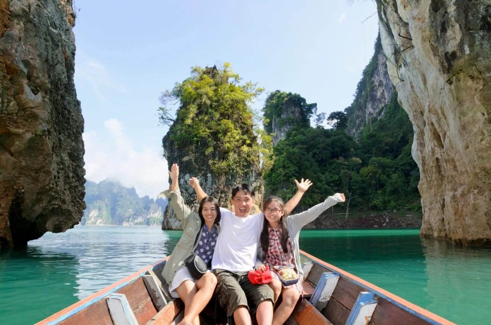 Three friends smiling on boat in turquoise lagoon