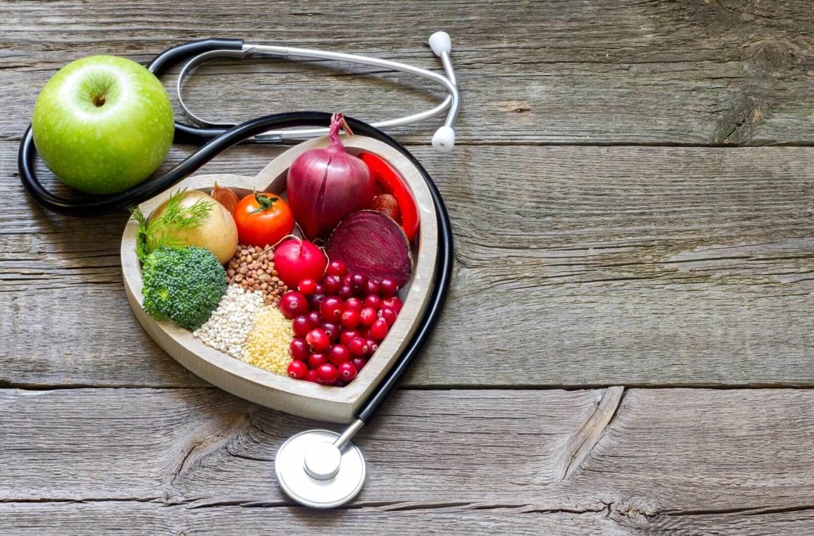 Heart-shaped bowl of healthy foods and stethoscope