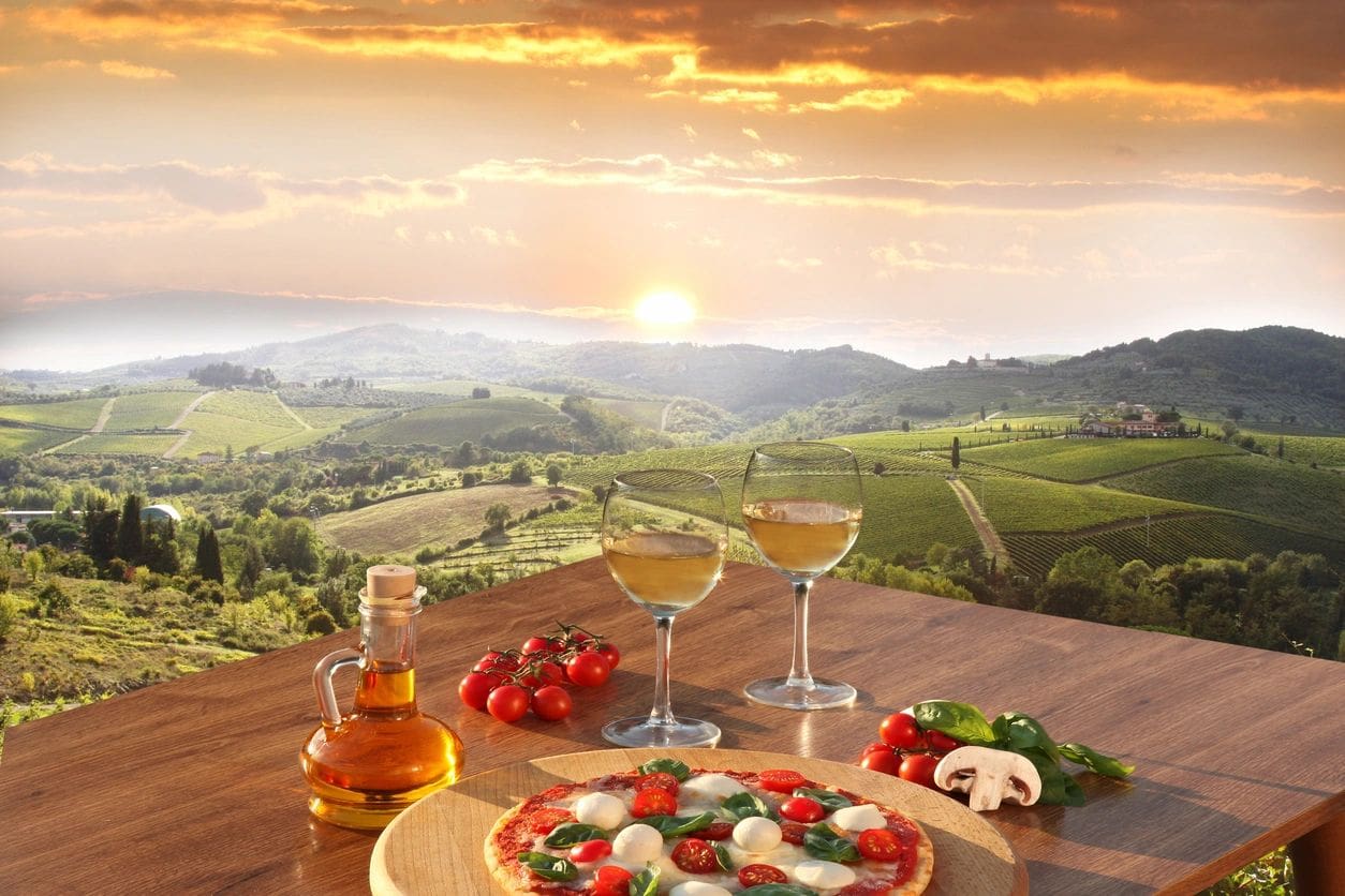 Margherita pizza and wine over vineyard sunset